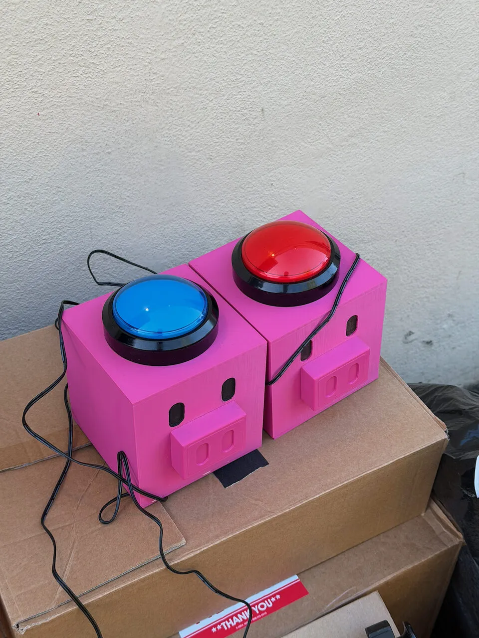 Two pig-shaped buttons the crew 3D-printed, one capped with a red arcade button, one with blue