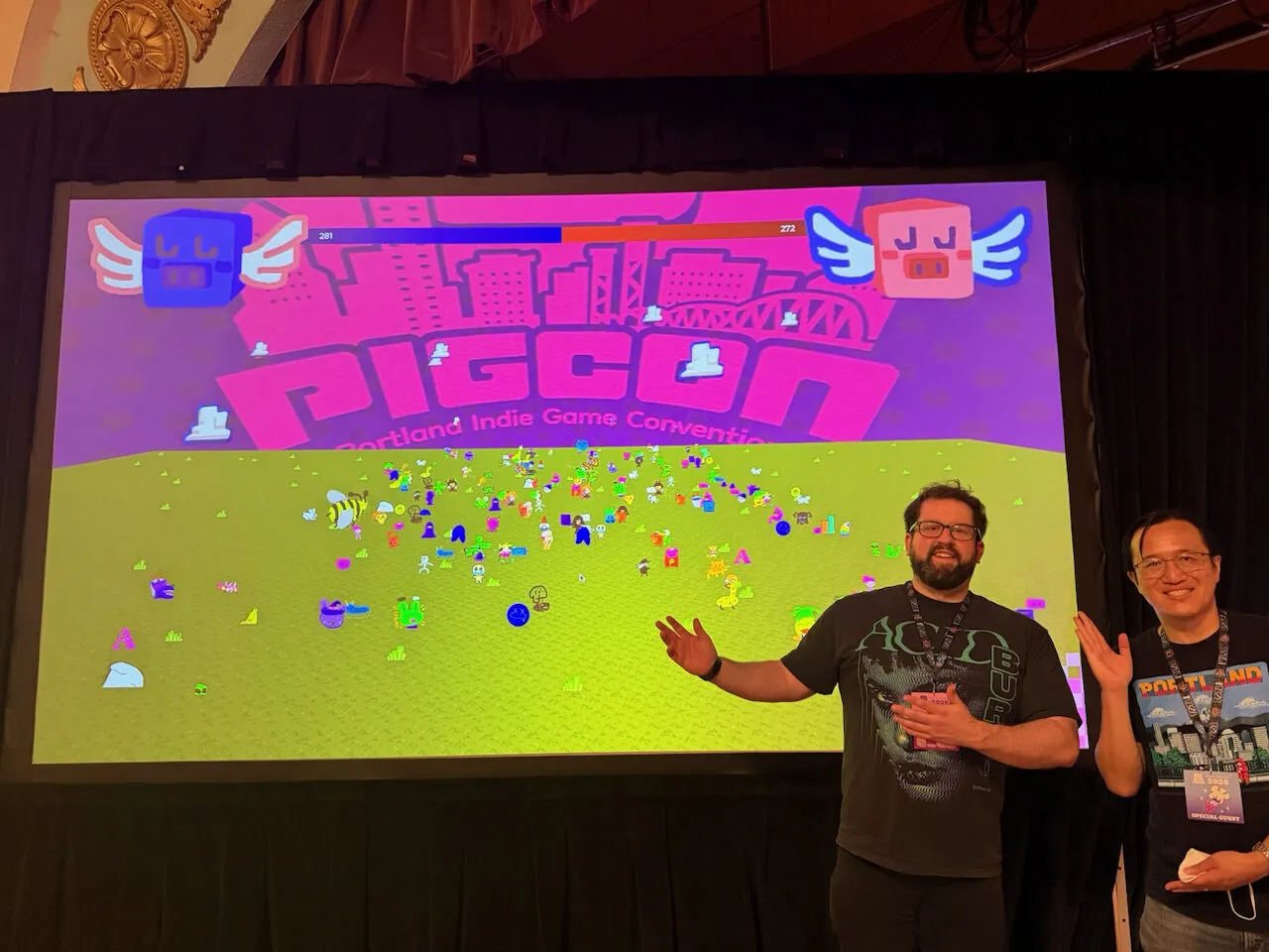 Brian (left) and Mike posing in front of the Plaza they built, the red-versus-blue tally and a field of creatures up on the big screen